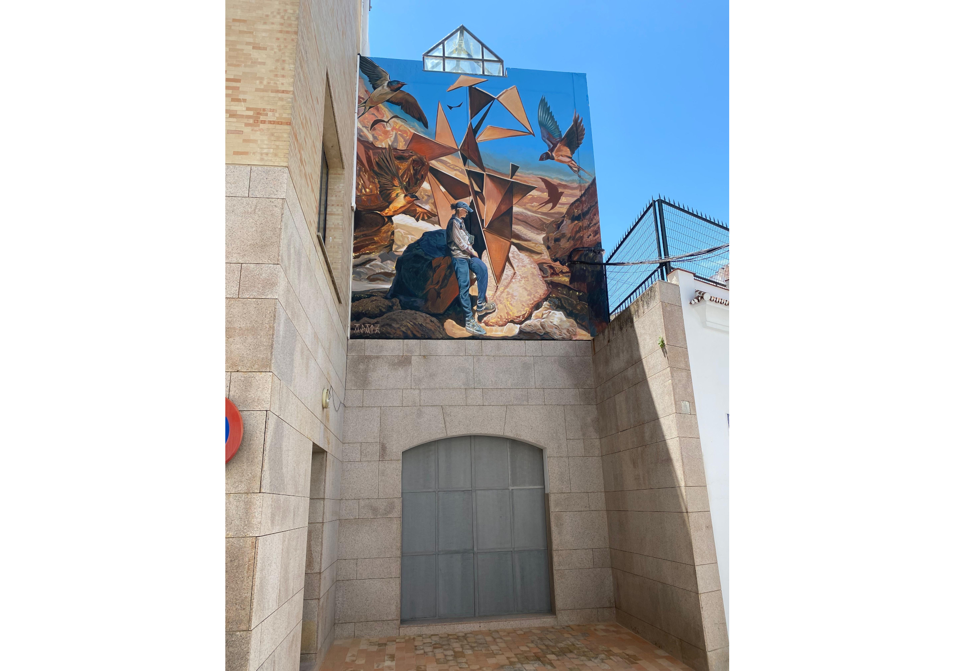fresque murale réalisée en Espagne à Baena qui représente un personnage dans un paysage rocailleux surréaliste et entouré d'oiseaux.